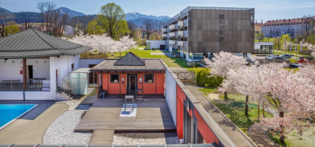 Moderner Dachgarten mit blühenden Bäumen und Bergen im Hintergrund.