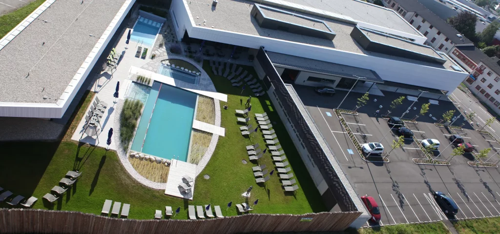 Dachterrasse mit Pool, grüner Rasenfläche und Liegestühlen von oben.