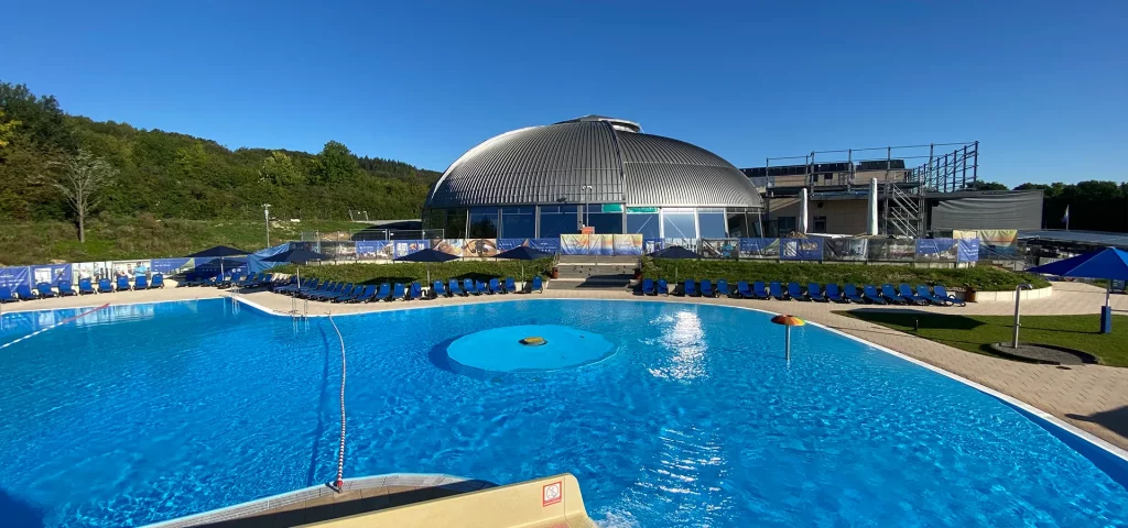 Rundes Schwimmbad mit futuristischer Kuppel und klarem Himmel.